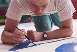 Signwriting the text on the banner that runs across the top of the backdrop.